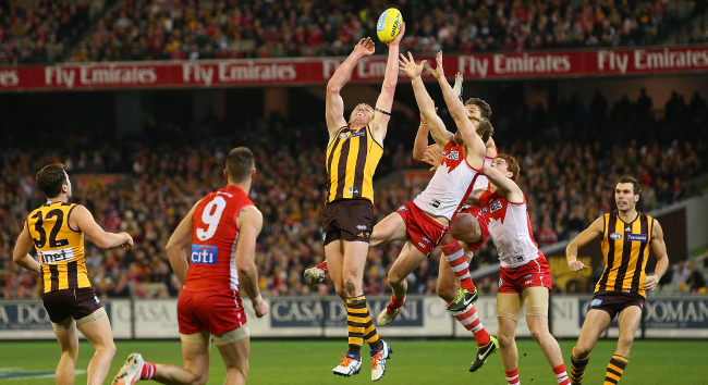 澳洲 AFL 球員在比賽中高高躍起爭搶橄欖球，Hawthorn Hawks 對戰 Sydney Swans 的激烈比賽場景。