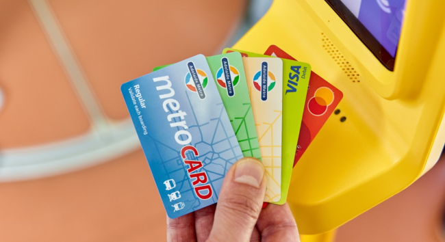 手持多張阿德雷德 MetroCARD 交通卡於驗票機前確認搭乘成功,畫面顯示驗證通過