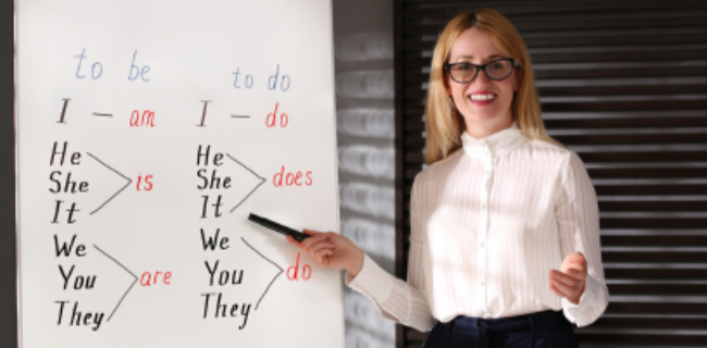 Giáo viên tiếng Anh giảng giải sự khác nhau giữa động từ "to be" và "to do" trên bảng trắng, thể hiện nội dung ngữ pháp cơ bản trong khóa học ELICOS.