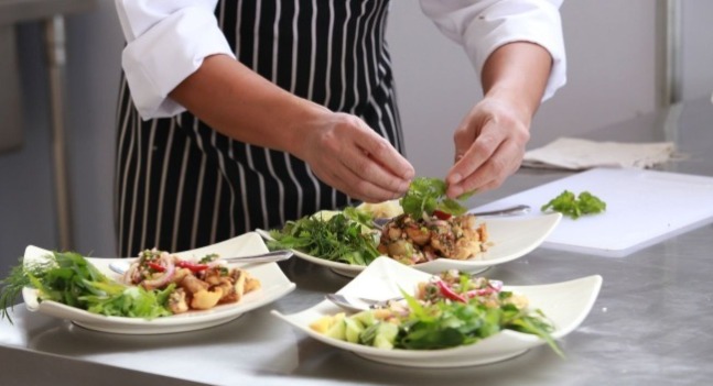 有一個身穿卡其色圍裙的男生在做櫥櫃工作 有黑色紅色耳機