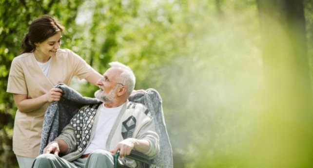 一個照護員推輪椅帶老人去公園