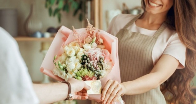 一個花藝師將一束花束遞給客人